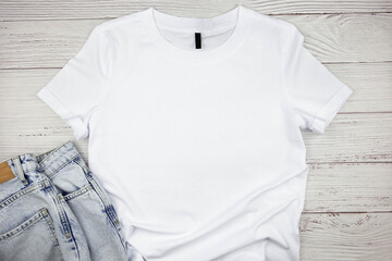 White womens cotton Tshirt mockup with blue jeans pants on wooden background. Design t shirt...