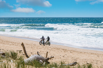 couple riding bicycle or fat bike on sunny beach