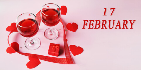 calendar date on light background with two glasses of red wine, red gift box and red hearts with...