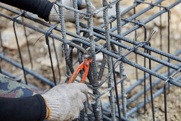 Cutting nipps steel fixer pliers holding on construction worker hand while his hand wear a gloves. Skills worker using pliers to tied together rebar steel with wire rod. Close up and selective focus.