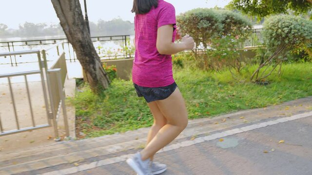 Taken from the back. The woman started to run in the morning to the park. She works out every morning by running to stay fit and lose weight.  Health care and sports concept.
