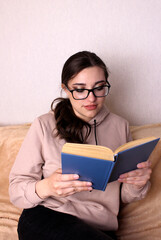 Girl student with glasses reads a book. Learning, reading, education