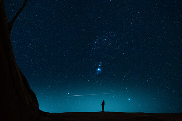 The girl silhouette stands on the hill and looking at the bright starry sky orion galaxy. Beautiful fantastic night landscape.
