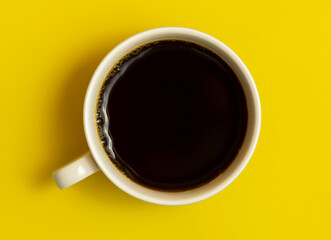 Top view of black coffee cup on yellow background