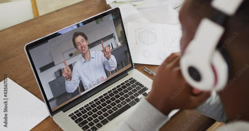 Poster African american male college student holding notes while having a video call on laptop at home