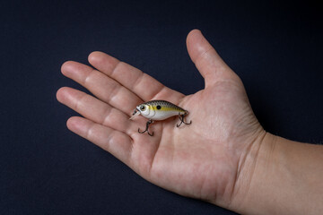 Artificial fishing lure in the shape of small chubby fish with shades of yellow held by the hand of a white woman. Widely used in fishing for tilapia and vorazez fish
