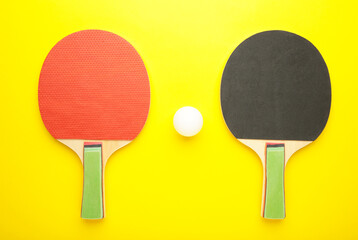 Ping pong rackets and balls on yellow background.