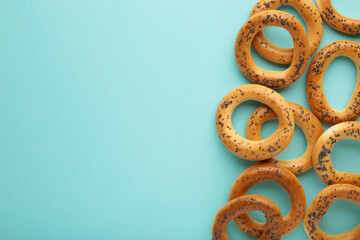 Whole bagel with poppy seeds on blue background with copy space