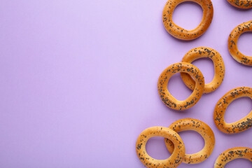 Whole bagel with poppy seeds on purple background with copy space
