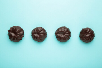 Chocolate covered marshmallows on blue background. Minimalism