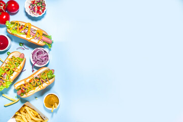 Barbecue grilled fastfood, Various traditional american hot dogs set with sausage, yellow mustard, ketchup and fresh vegetables salad, top view on bright blue background with french fries