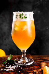 A glass of cold beer with lemon and mint, traditional latin american drink michelada on dark background vertical photo