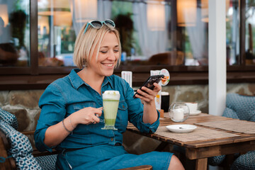 Young woman drinking enjoying matcha green tea latte in summer morning in cafe.