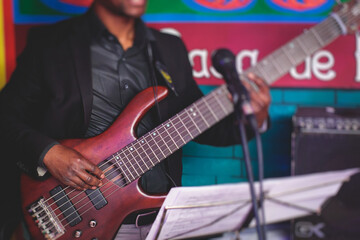 Concert view of an african-american musician with electric bass guitar player during band...