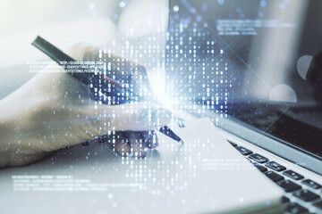 Creative concept of code skull illustration and hand writing in notebook on background with laptop. Hacking and phishing concept. Multiexposure