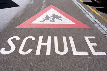 Attention traffic sign watch out for school kids with text Schule (German, translation is school)...