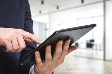 Businessman hand clicks on the screen of a digital tablet in conference room, close up. Internet Work Concept