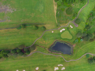 In the photo there is a green meadow, mountainous terrain, hills overgrown with grass. Small body of water. There are many paths. There are no houses and people. Aerial photography. View from above.
