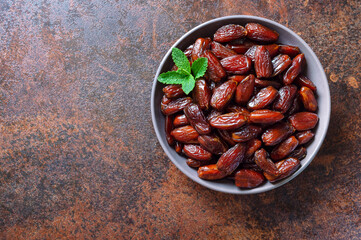 Sun-dried dates fruits in a ceramic bowl. Organic dried fruits.