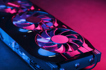 Large and powerful graphics card with three fans with blue pink light.