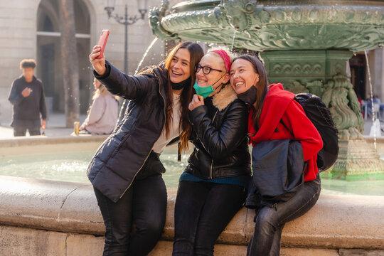 Candid Portrait Of Three Female Friends Taking A Selfie With A Smart Phone