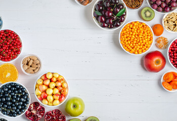 Fresh berries, fruits, nuts on a white wooden background. The concept of healthy eating. Food contains vitamins and trace elements. Copy space.