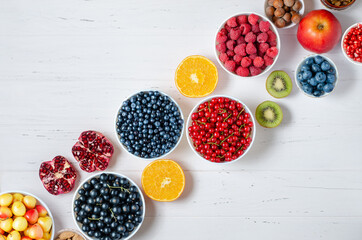 Fresh berries, fruits, nuts on a white wooden background. The concept of healthy eating. Food contains vitamins and trace elements. Copy space.