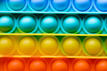 Pop It texture colorful rainbow background, silicone sensory anti-stress Fidget toy, copy text space. Calming tools, stress reliever popping, trendy children bubble toys, summer, bright, LGBT concept