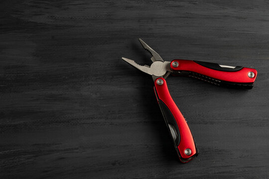 Pinzas multiusos de color rojo con un fondo gris. Herramienta de mano multiusos
