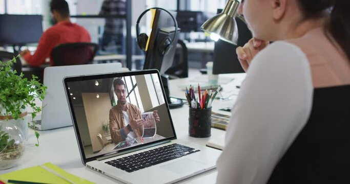 Caucasian woman having a video call with male colleague on laptop at office