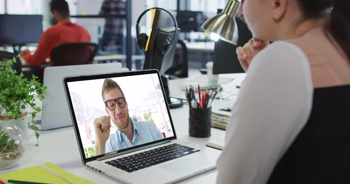 Caucasian woman having a video call with male colleague on laptop at office