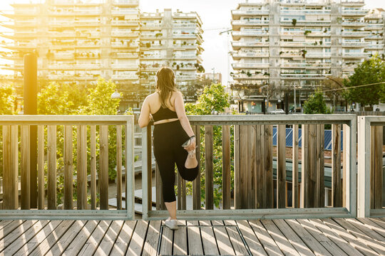 Back View Of Curvy Young Athletic Woman Stretching After Workout At Sunset - Workout Outdoors Concept