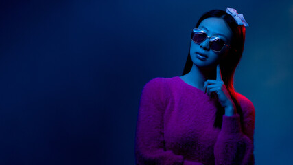 Ultraviolet girl. Advertising banner. Futuristic portrait. Blue red color neon light confident glamour Asian woman in pink in sunglasses isolated on dark night empty space background.