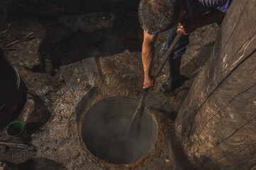 Obraz premium Mezcal master cooking the pineapple from the agave to extract the juice and turn it into mezcal, he uses a pot to remove the juice from the oven.