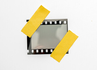 blank or empty 35mm dia film frame fixed by two yellow adhesive strips on white background, cool...