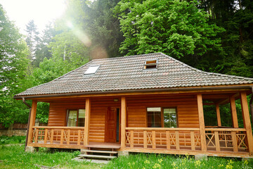 Modern wooden cabin in a forest in the summer. Wooden terrace of wooden house
