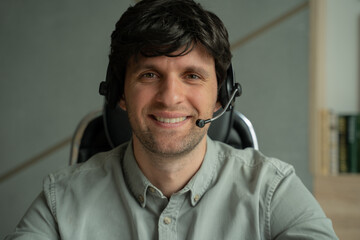 Man in a shirt is using a headset in the office, a man is looking and talking into the camera while sitting at a desk.