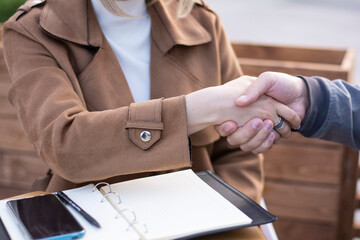 Closeup handshake of a man and a woman who are sitting opposite each other on the street in the city