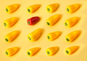 Pattern of yellow peppers on yellow background that is broken by a red bell pepper.