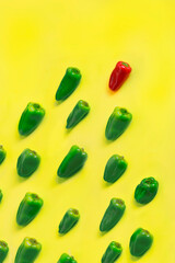 Pattern of green peppers chasing a red bell pepper on yellow background. Top view and food background.