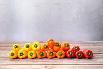 Front view of colorful orange, red and yellow peppers stacked by color.