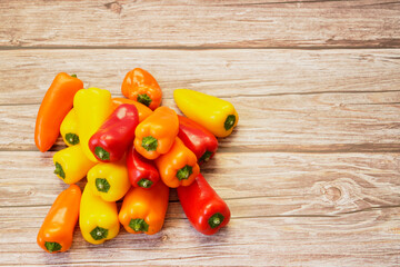 Top view of colorful orange, red and yellow peppers paprika on wooden table.