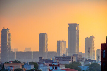 dawn shot of skyscrapers houses shot partially hidden in fog with the warm orange of dusk showing...