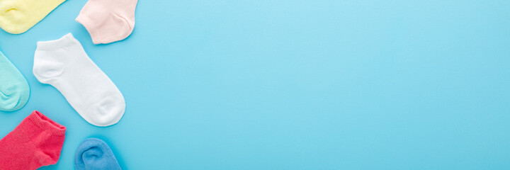Colorful kid short socks on light blue table background. Pastel color. Closeup. Clothes wide banner. Empty place for text. Top down view.