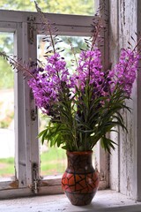 Fototapeta na wymiar beautiful bouquet summer flowers of Ivan-tea or blooming Sally. Medicinal plant willow-grass in vase onwindowsill in village house. Wildflowers