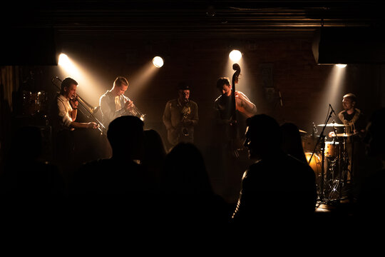 WIDE People dancing during concert of a modern jazz band playing on a stage of a small crowded venue - Powered by Adobe