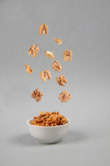 walnut pouring into a bowl isolated on gray background - flying food concept