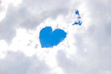 In the snow-white clouds in the gap there is a heart from the blue sky, an angel is nearby. Place...