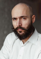  white bald man with a beard and mustache in a white shirt close up