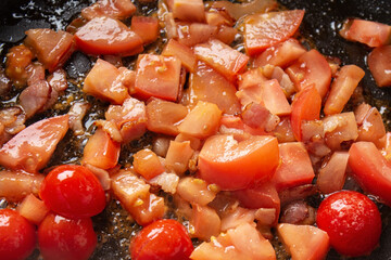 frying tomatoes and bacon in a frying pan close-up. Cooking carbonara